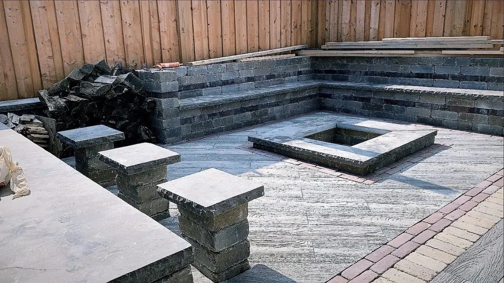 Backyard hardscape with stone bench seating, fire pit, and paver patio